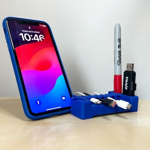Phone on a stand with cables, pen, and USB drive in a desk organizer.